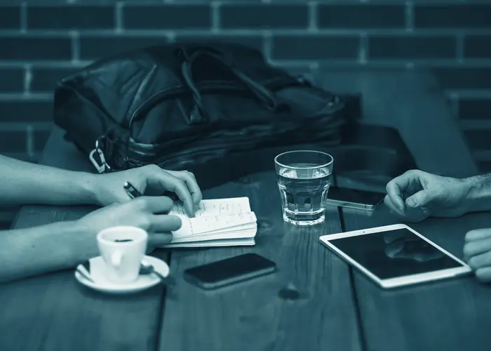 Dos personas en una reunión de trabajo con tablet y teléfono